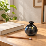 Small dark Kouzan bud vase styled with a book and pencil on a wood desk; accessories not included