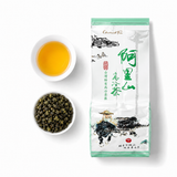 Cup of brewed Alishan Xiding oolong tea beside loose rolled tea leaves and the tea pouch