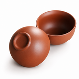 Matching Yixing Zisha clay teacups showing smooth reddish-brown ceramic texture on a white background