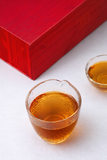 Rainforest Tea cup with amber liquor beside luxury red Dian Hong tea gift box from Xishuangbanna Yunnan 