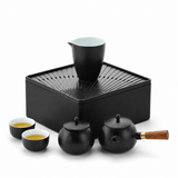 Black tea tray with pitcher, teapot, three cups, and portable carrying case