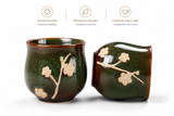 Close-up of handcrafted ceramic tea cups with green glaze and floral pattern, showcasing premium craftsmanship and texture