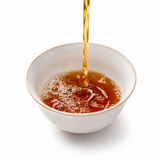 Narcissus Oolong Rock Tea liquor being poured into a white tea cup with rich amber color