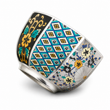 Angled silver-plated tea cup showing detailed blue, teal, and floral decorative panels on a white background.