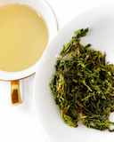 Brewed Lushan mist green tea with tea leaves on a white plate