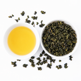 Loose Alishan oolong tea leaves beside brewed tea