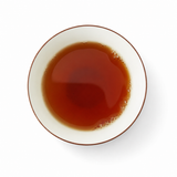 Top view of taiwan jade black tea in a white teacup with a thin brown rim on a clean white background