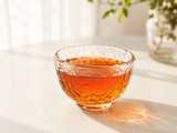 Jade Black Tea brewed in a textured glass cup with warm amber color and soft natural light