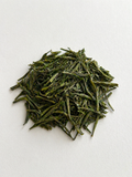 Loose Tianmu Qingding green tea leaves arranged on a clean white background