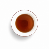 Amber Assam black tea in a white ceramic cup on a clean white background