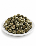 Hand-rolled Jasmine Pearl Green Tea pearls displayed on a white plate with clean white background