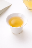White porcelain teacup filled with pale golden jasmine silver needle tea