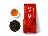 Cup of amber tea with loose Alishan black tea and red tea pouch