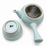 Pale blue teapot with metal mesh infuser beside the inverted cup showing its Kōrin Kiln base mark