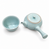 Overhead view of the pale blue side-handle teapot with lid and one matching tea cup