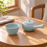 Pale blue Japanese teapot and matching cup on a sunlit wooden table